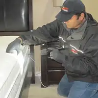 Bed bug inspection technician checking a mattress and bed frame for signs of infestation in Tampa, FL