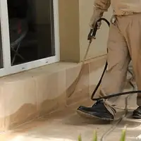 General pest control technician spraying exterior perimeter around a home in Tampa, FL