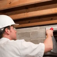 Termite inspection technician checking a basement wall and framing for termite activity in Tampa, FL