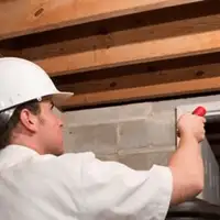 Termite inspection technician checking a basement wall and framing for termite activity in Tampa, FL